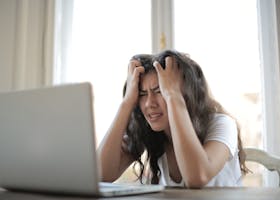 Frustrated woman struggling with remote work stress and digital challenges indoors.