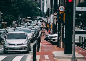 Urban street scene with heavy traffic and cyclists in a bustling city environment.