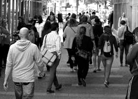 A bustling street scene capturing diverse pedestrians walking outdoors in an urban setting.